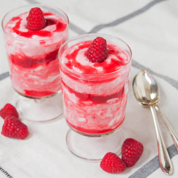 two glasses of raspberry fool with spoons to right side.