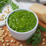 dish of arugula pesto with arugula leaf to side.