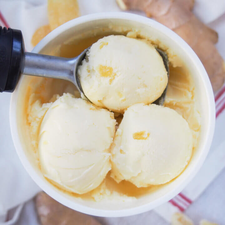three scoops of ginger ice cream at top of container with scoop under one of them.