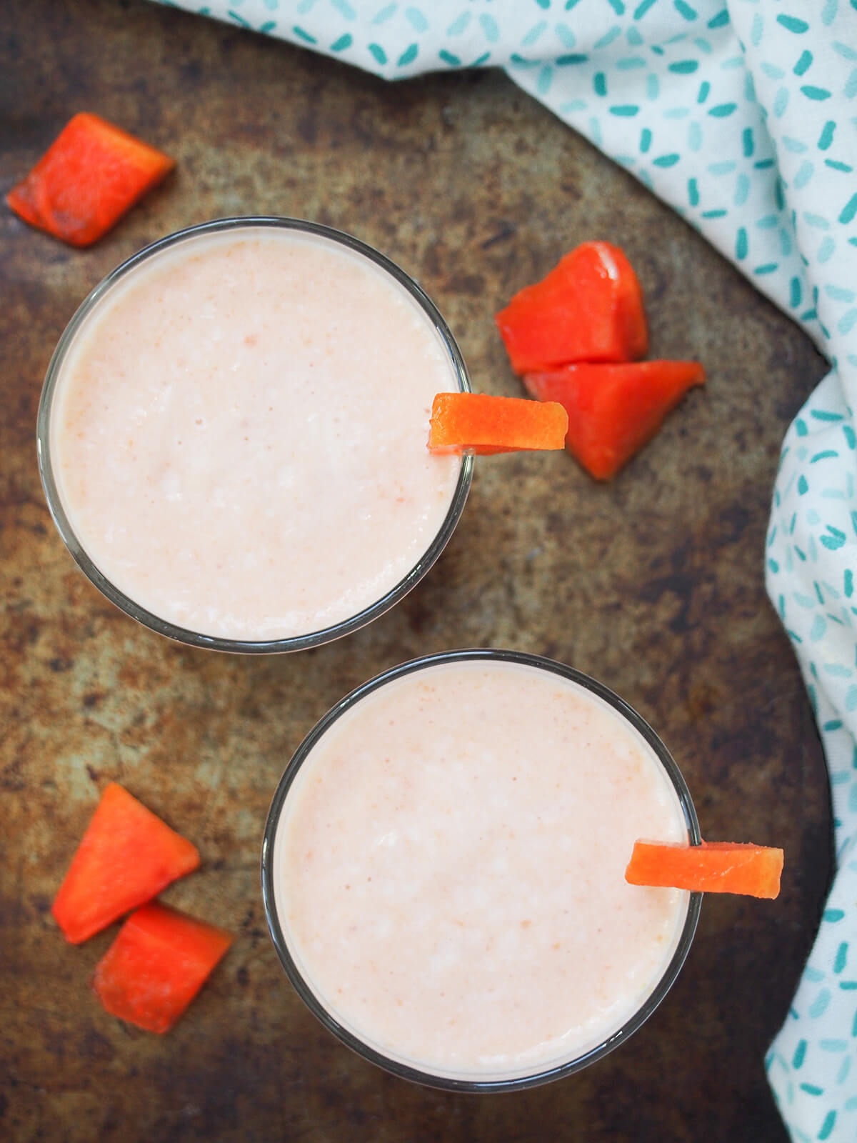 overhead view of two glasses of papaya milkshake.