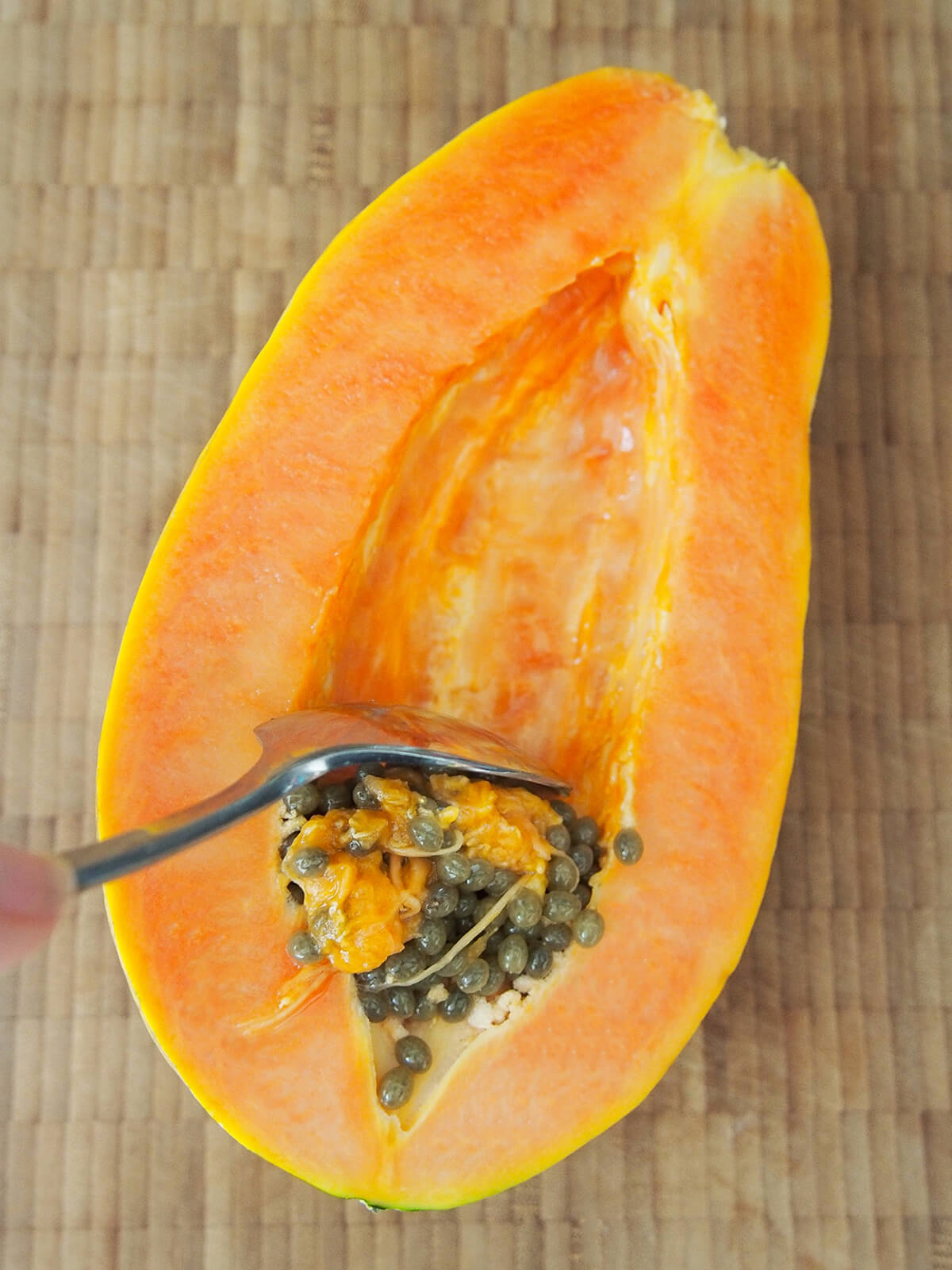 scooping seeds out of a papaya half