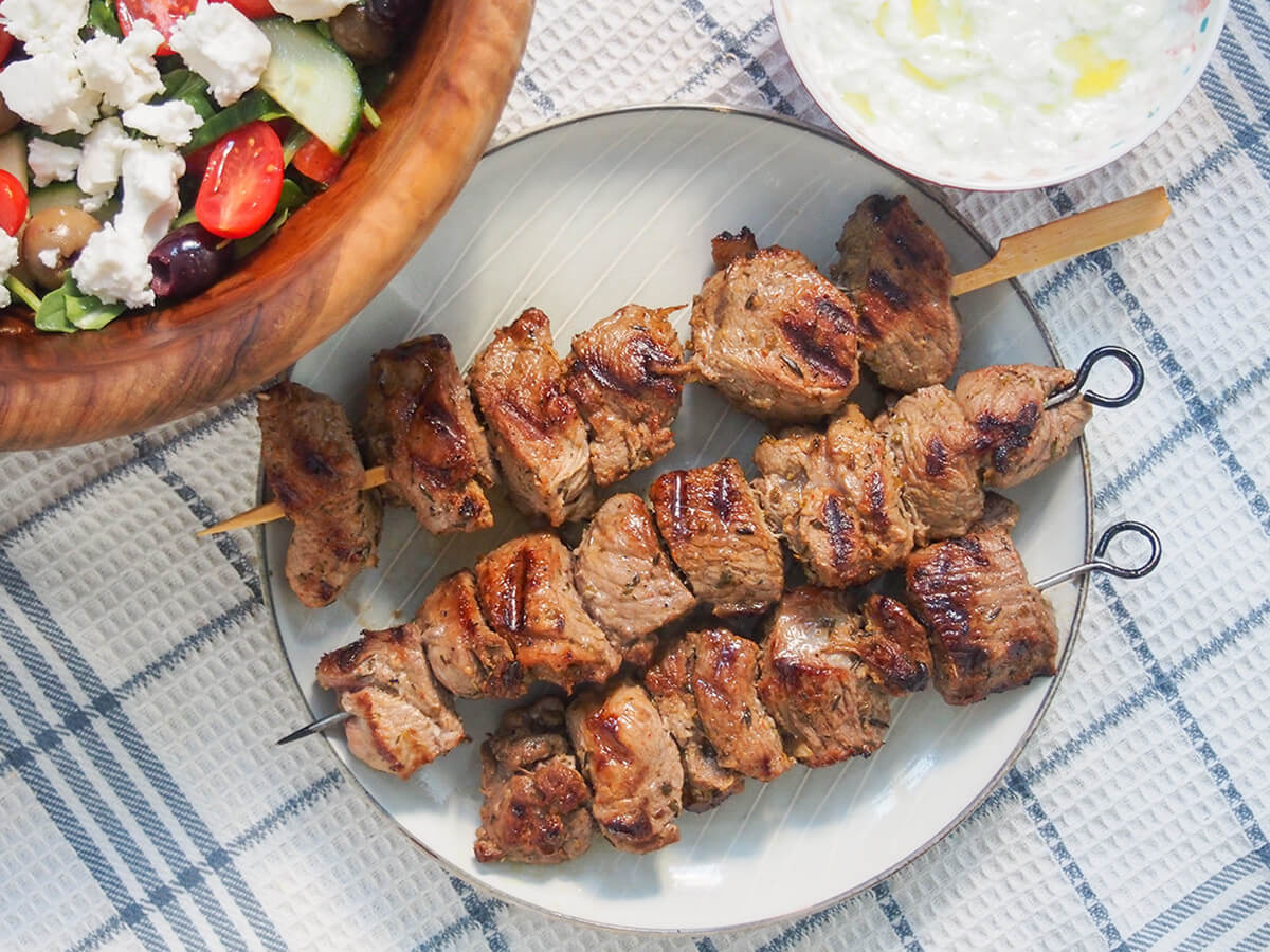Greek marinated lamb souvlaki skewers on plate three Greek lamb souvlaki on a plate.