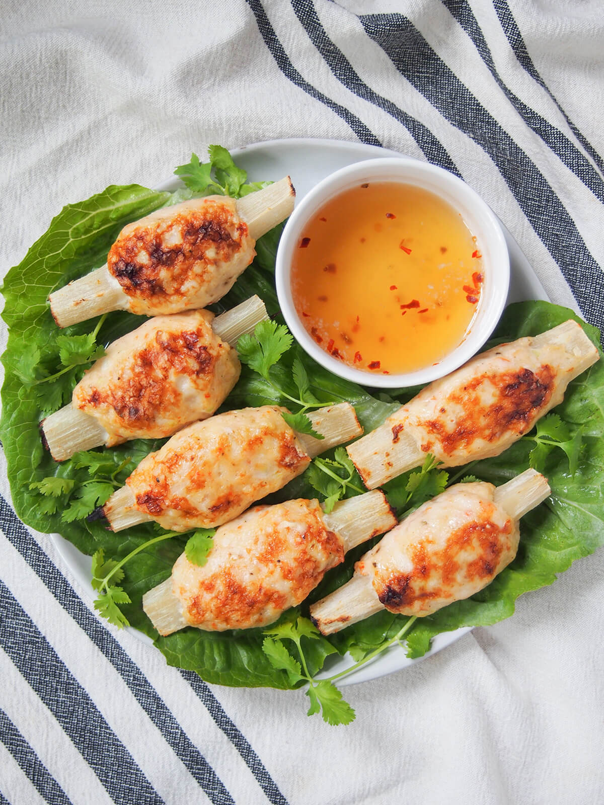 plate of Vietnamese sugarcane shrimp with bowl of dipping sauce at top of plate from overhead.