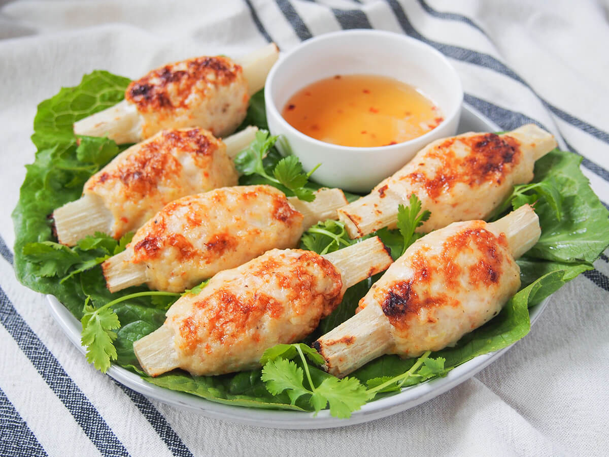 plate of Vietnamese sugarcane shrimp on lettuce with small bowl of dipping sauce to back
