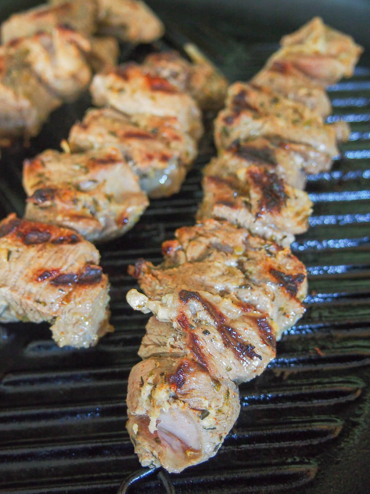grilling Greek lamb souvlaki skewers of lamb cooking on grill.