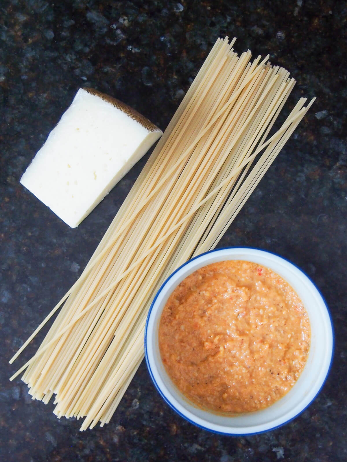 piece of cheese, spaghetti and bowl of sauce.