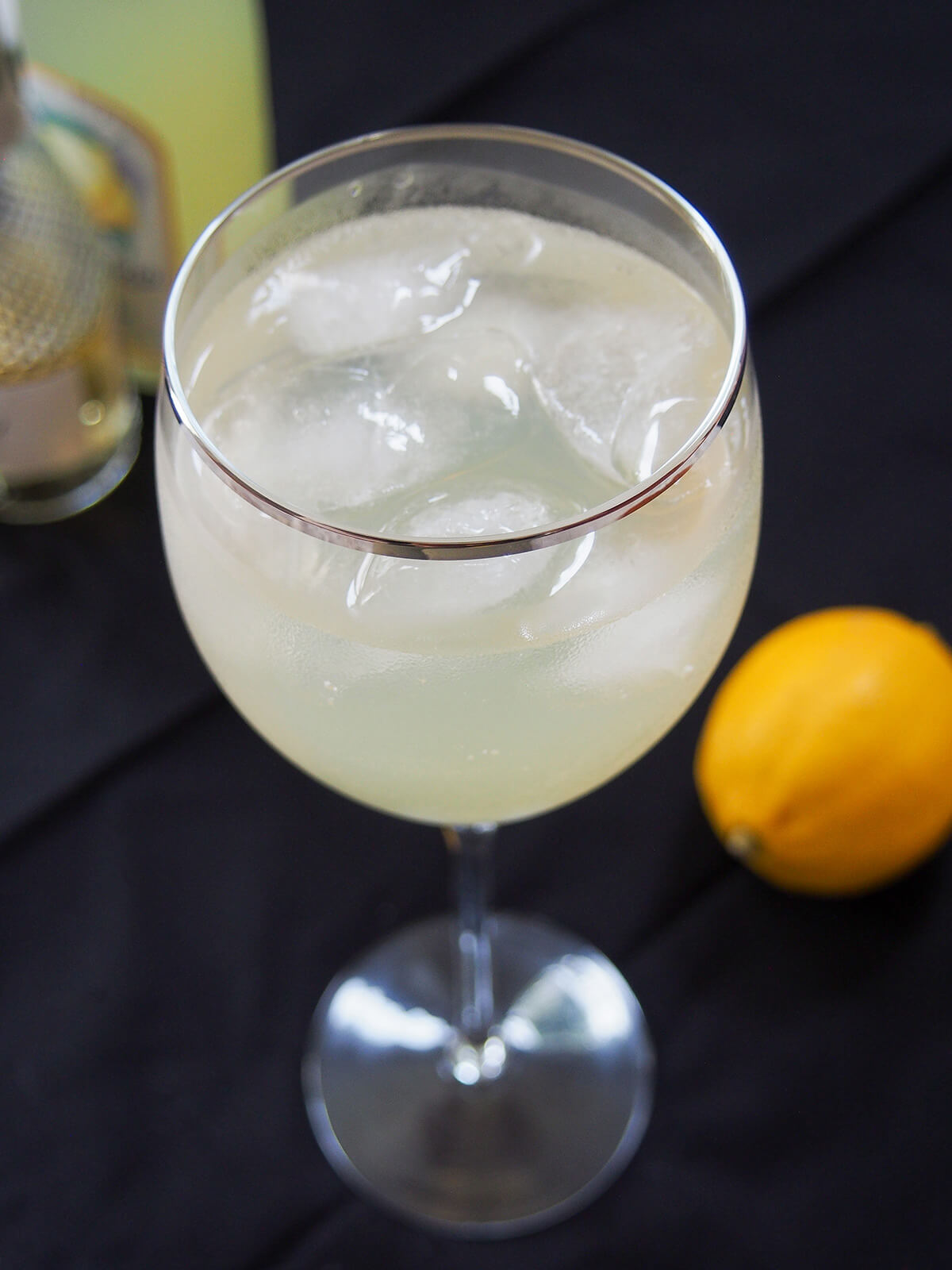 glass of limoncello spritz with lemon hazy in background.