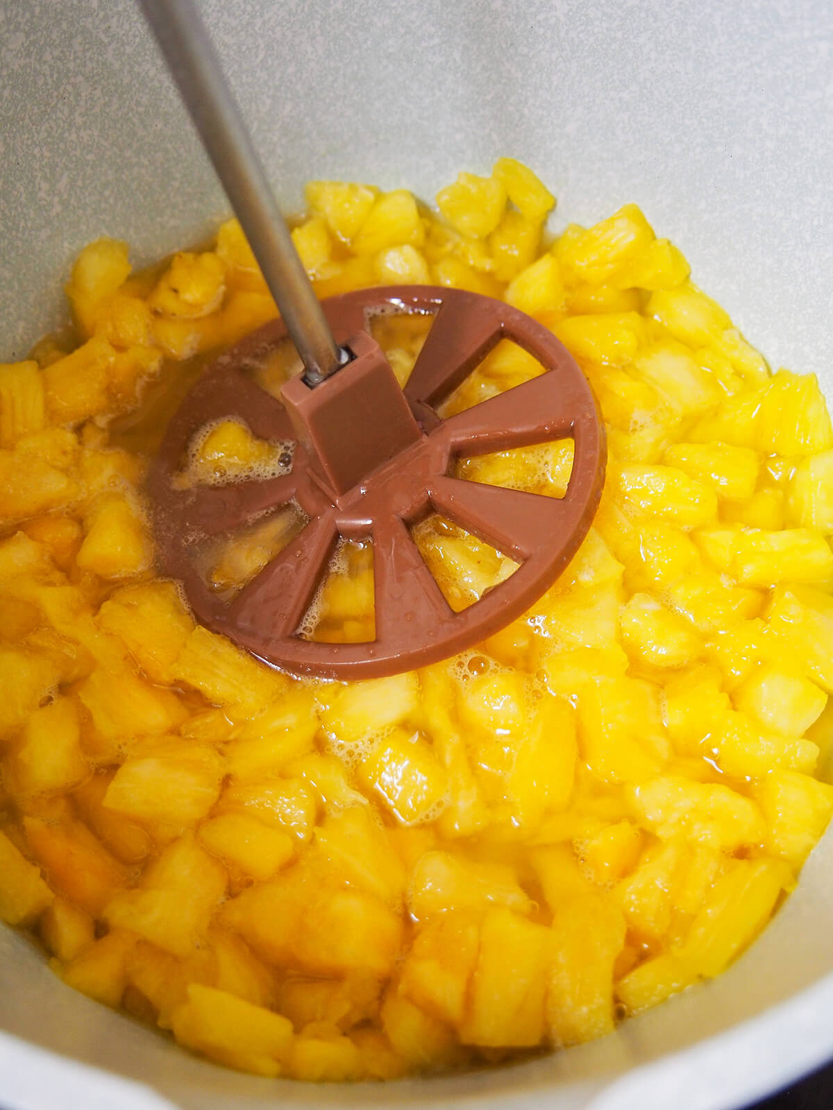 mashing pineapple in pot for filling.