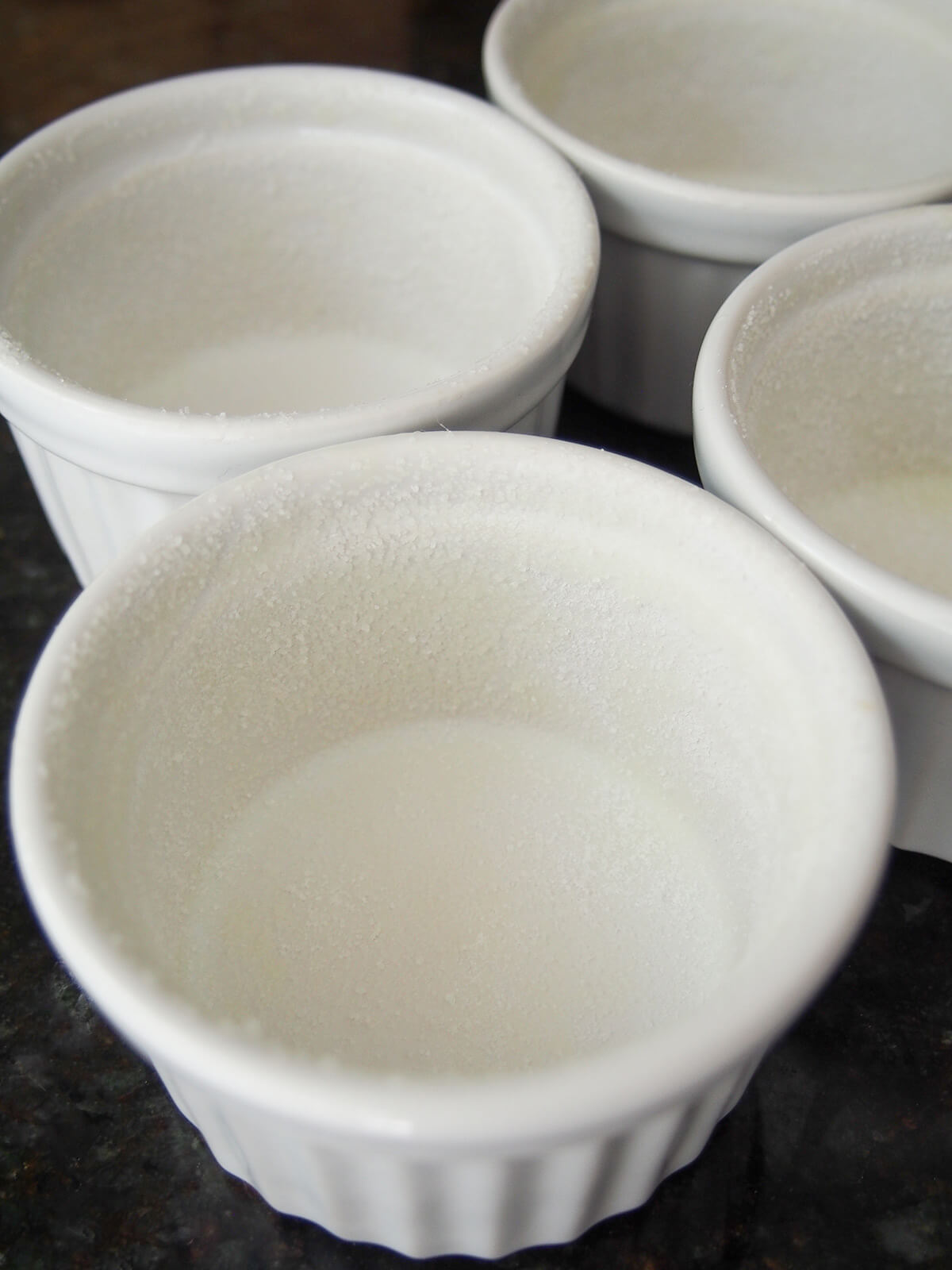 ramekins with sugar dusted inside held on by butter.