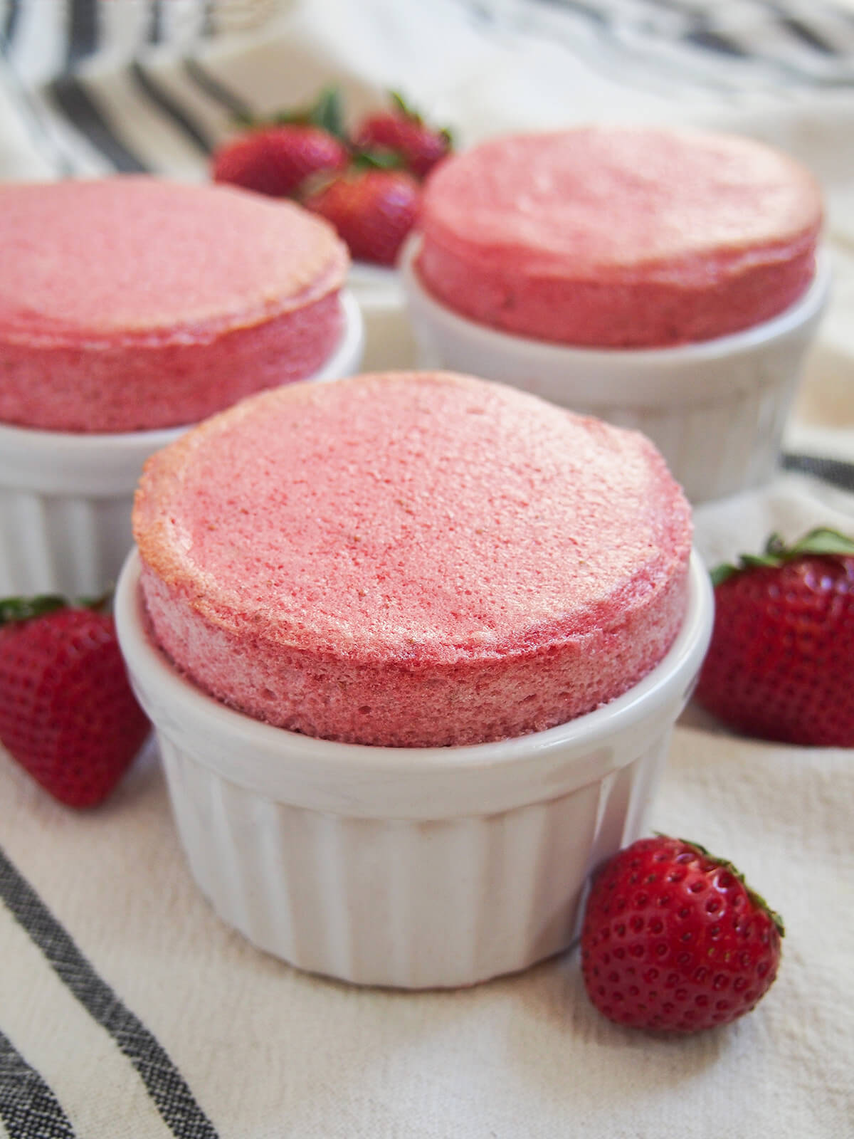 three ramekins of strawberry souffle with one in full at front.