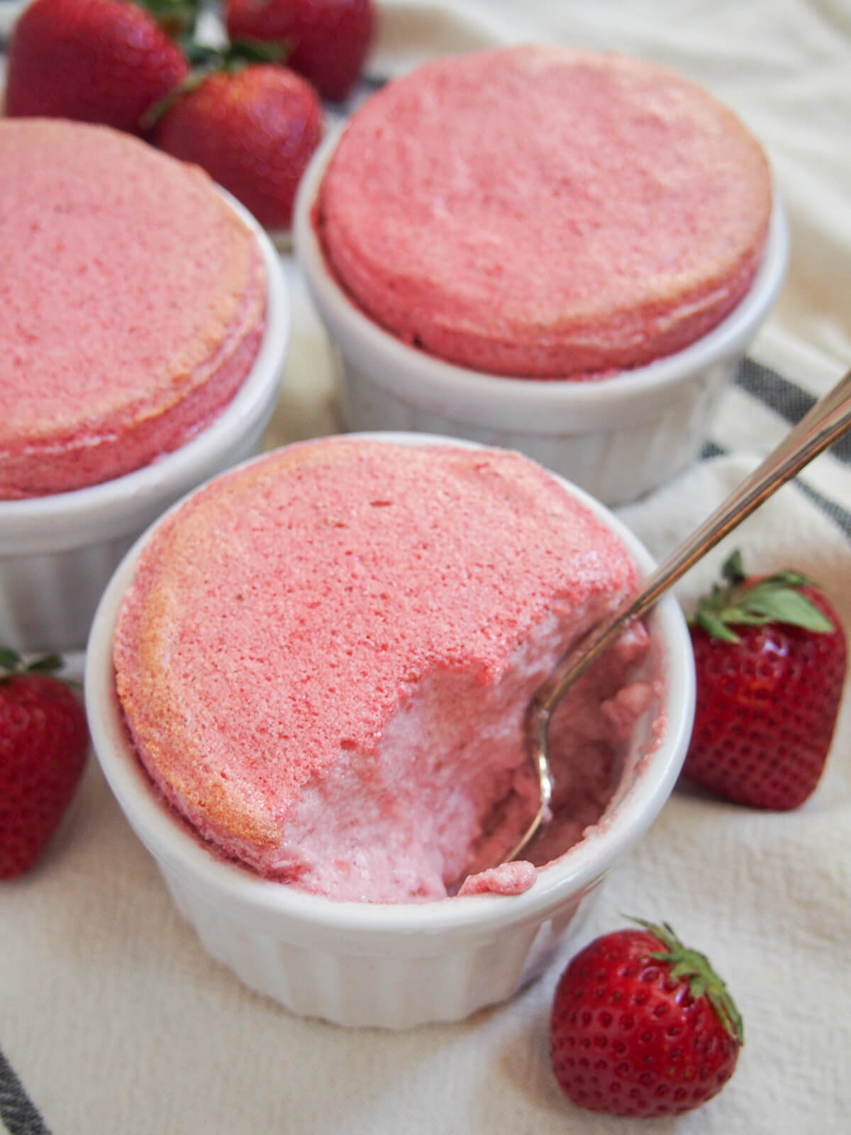 spoon in dish of strawberry souffle with others behind.