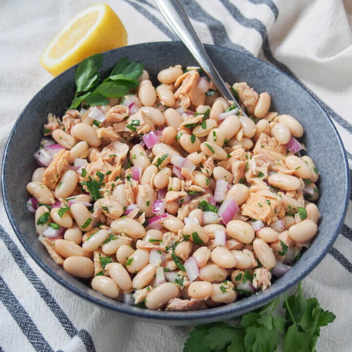 bowl of Tuscan white bean and tuna salad with spoon in it at back.