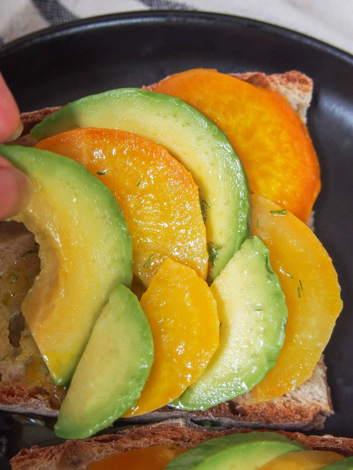 placing slices of avocado and golden beet on piece of bread in overlapping layers.