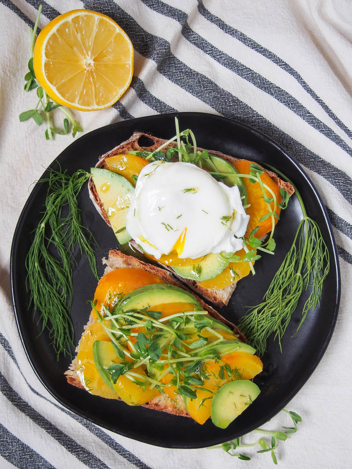 overhead view of two slices of bread topped with avocado and golden beet with one topped with an egg.