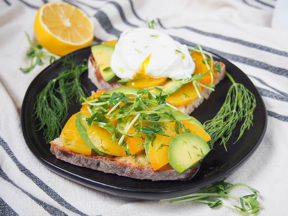 slices of avocado tartine with golden beet with dill decorating plate and lemon behind.