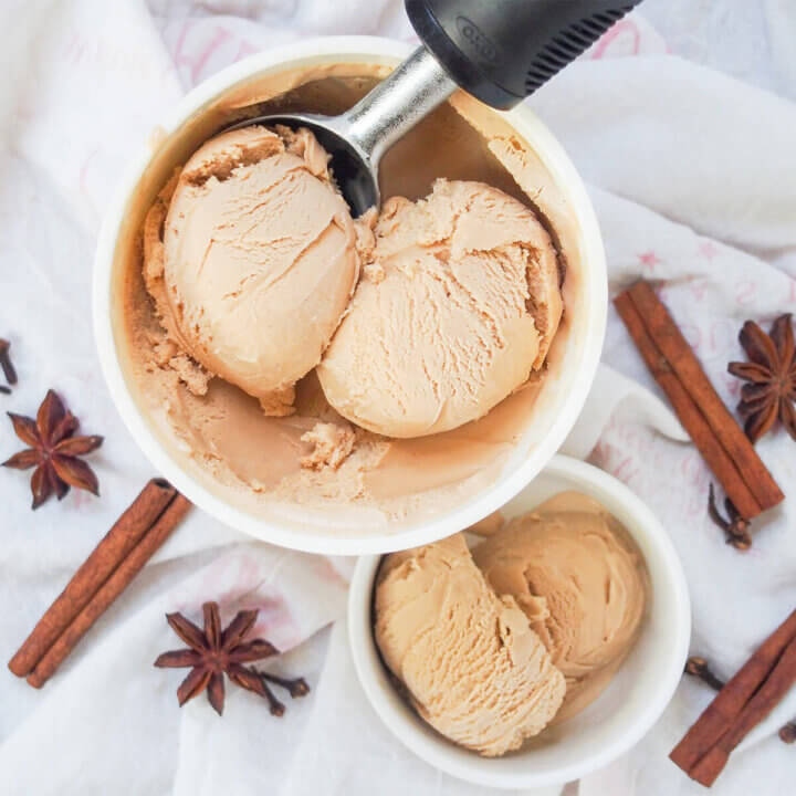 tub of chai ice cream with scoop in it with spices around.