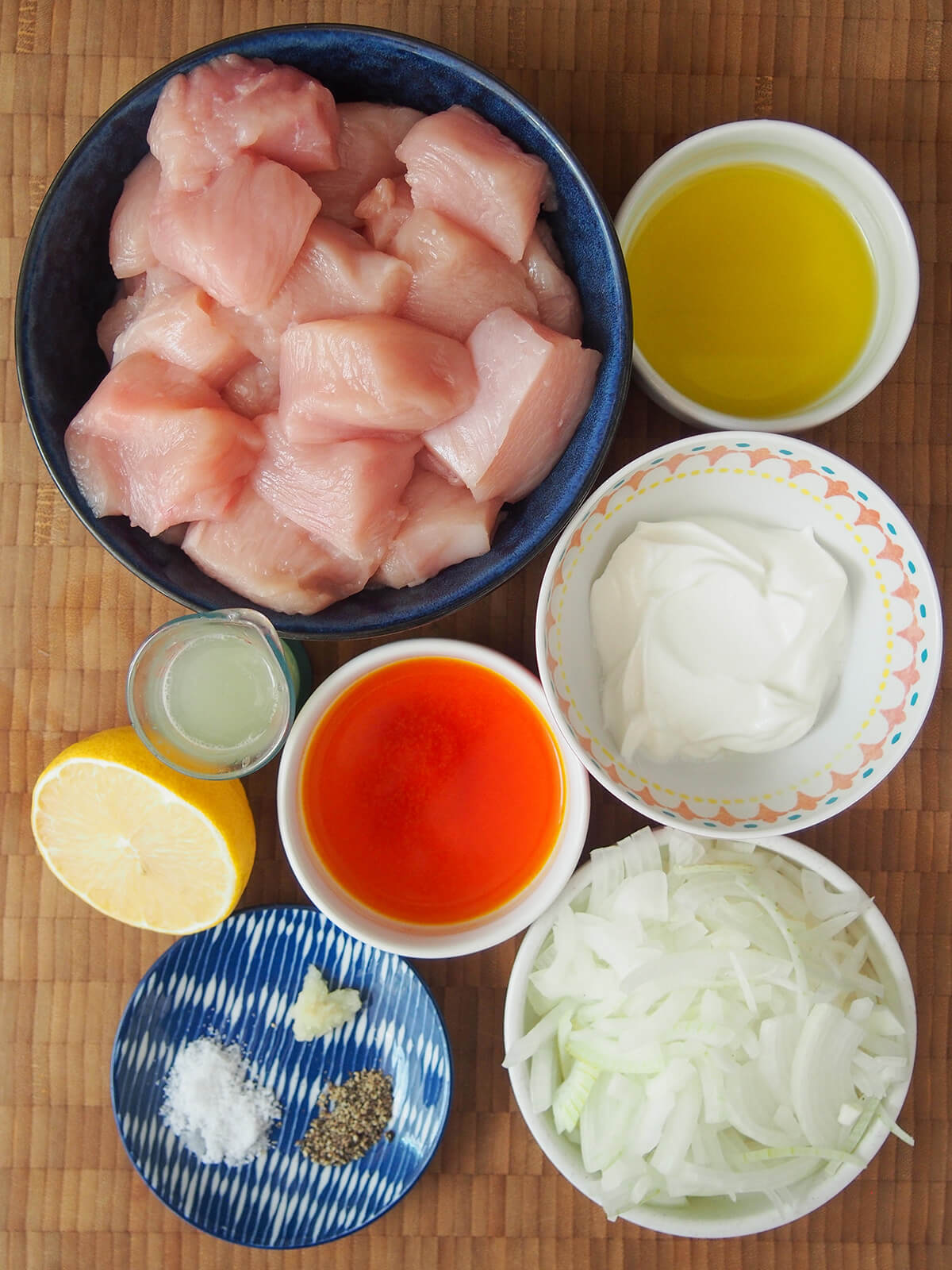 bowls with diced chicken, yogurt, sliced onion, olive oil, saffron water and lemon.