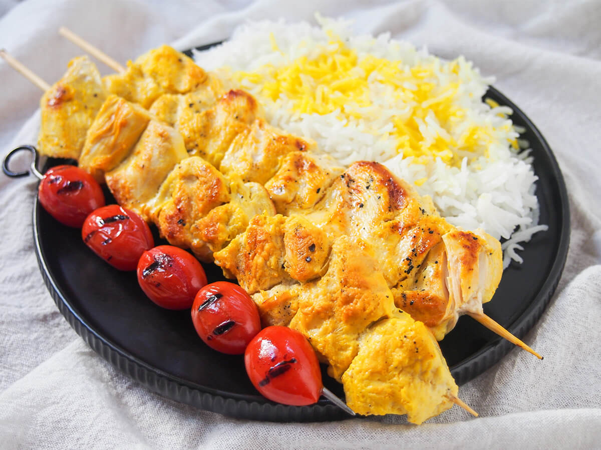 jujeh kabab on plate with tomatoes in front, rice behind/