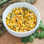 bowl of masala corn with cilantro below bowl.