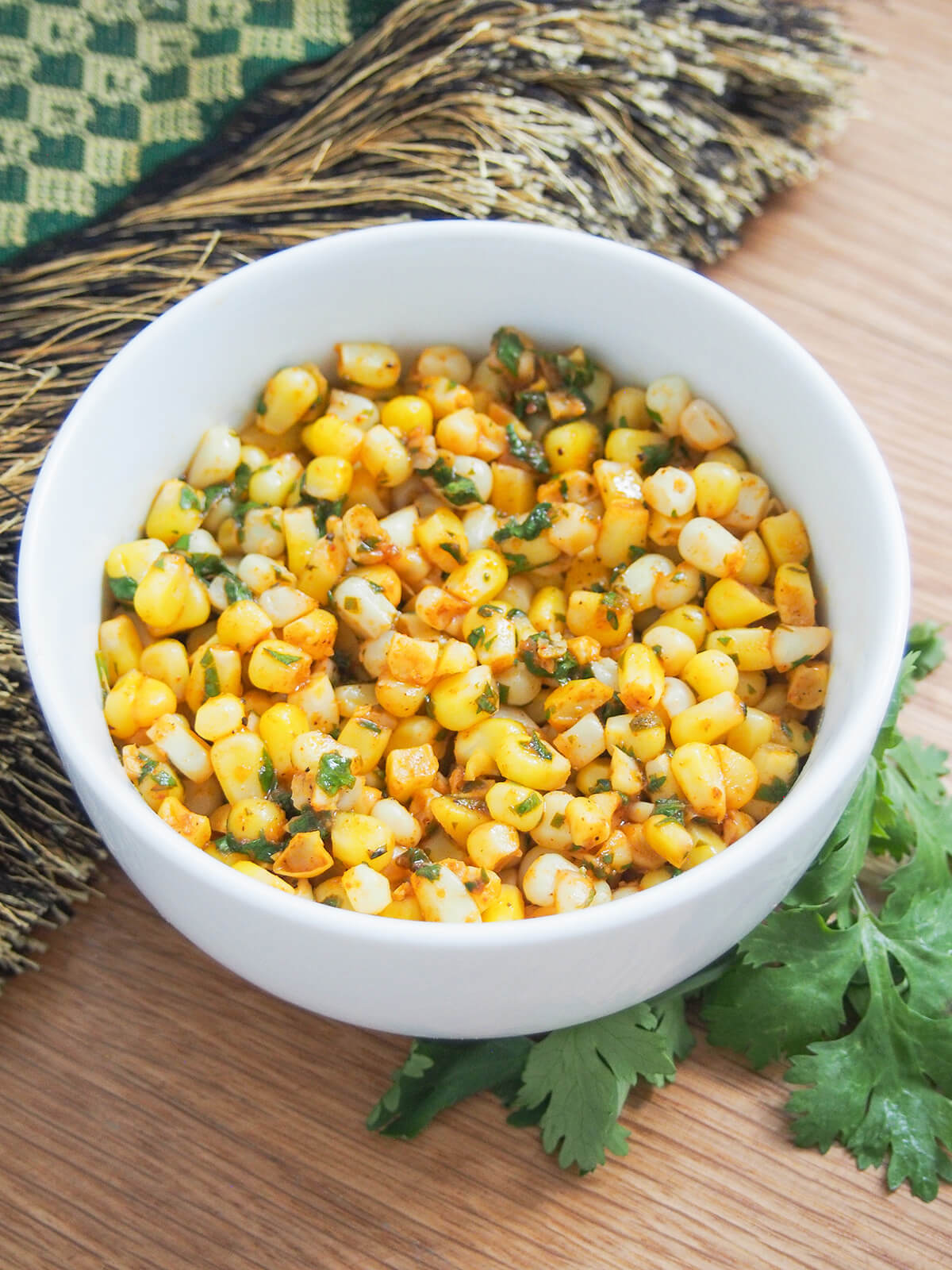 bowl of masala corn with tufted cloth behind bowl.