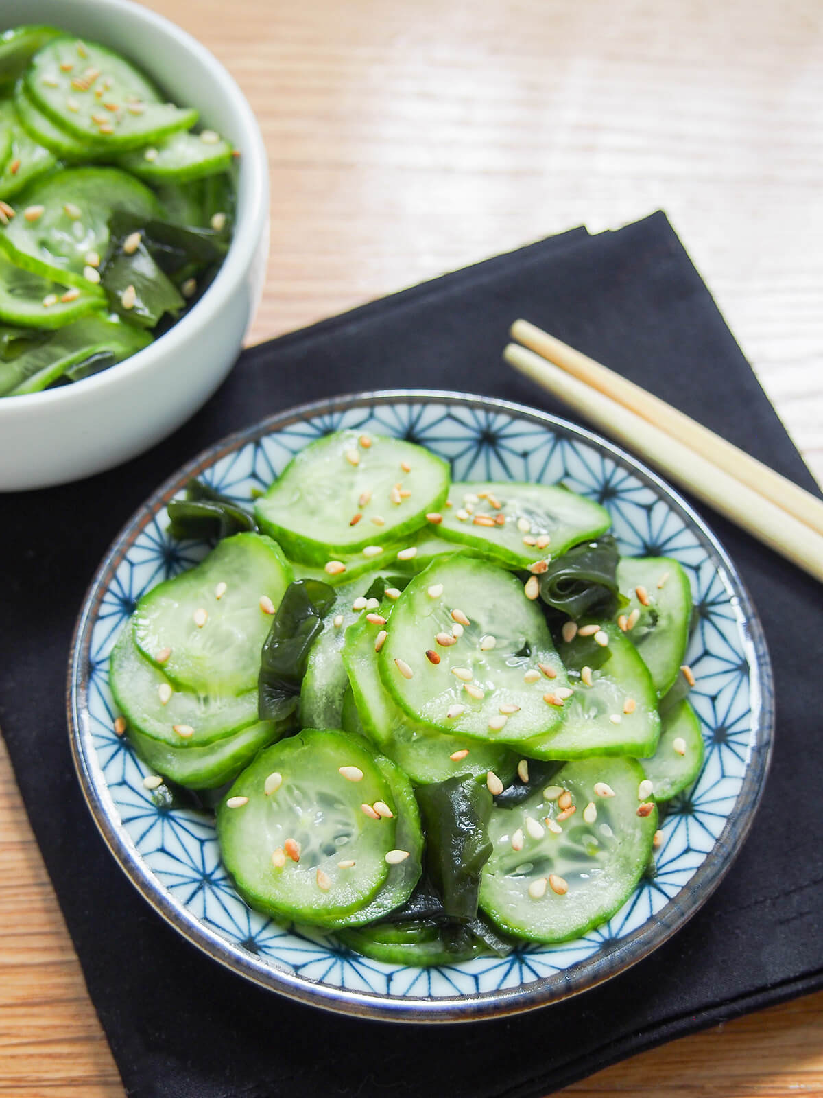 plate of Japanese cucumber salad, sunomono with end of chopsticks on cloth behind.