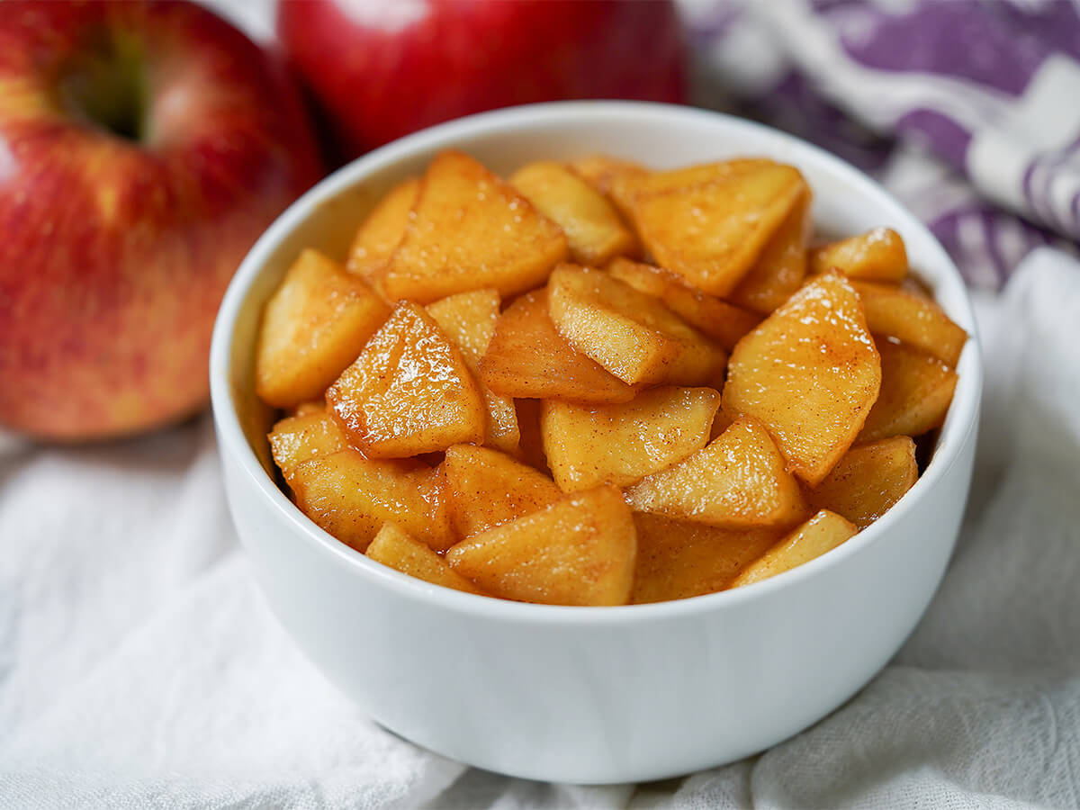 bowl of caramelized apples bowl of caramelized apples with apples in background behind.