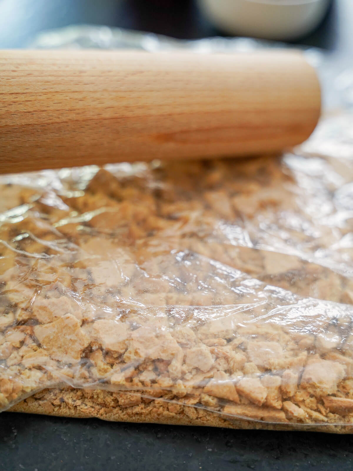 crushing biscuits/cookies in a bag with a rolling pin.
