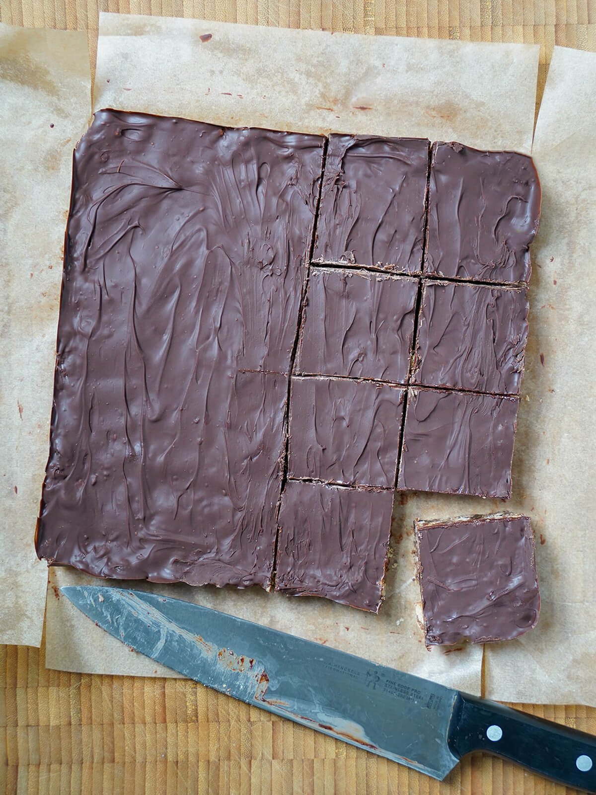 cutting block of chocolate tiffin into squares, with knife below partly cut block.