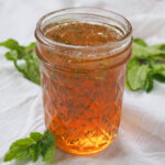 side view of jar of mint jelly with sprigs of mint behind and to side.