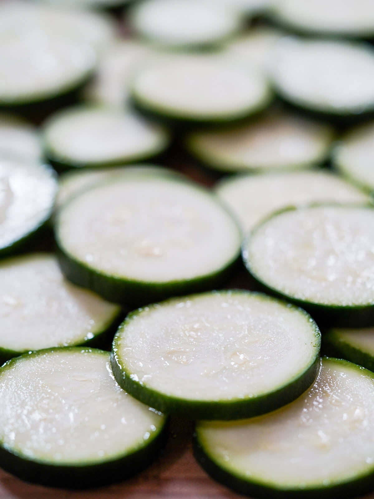 slices of zucchini stacked on each other with water droplets on the slices.