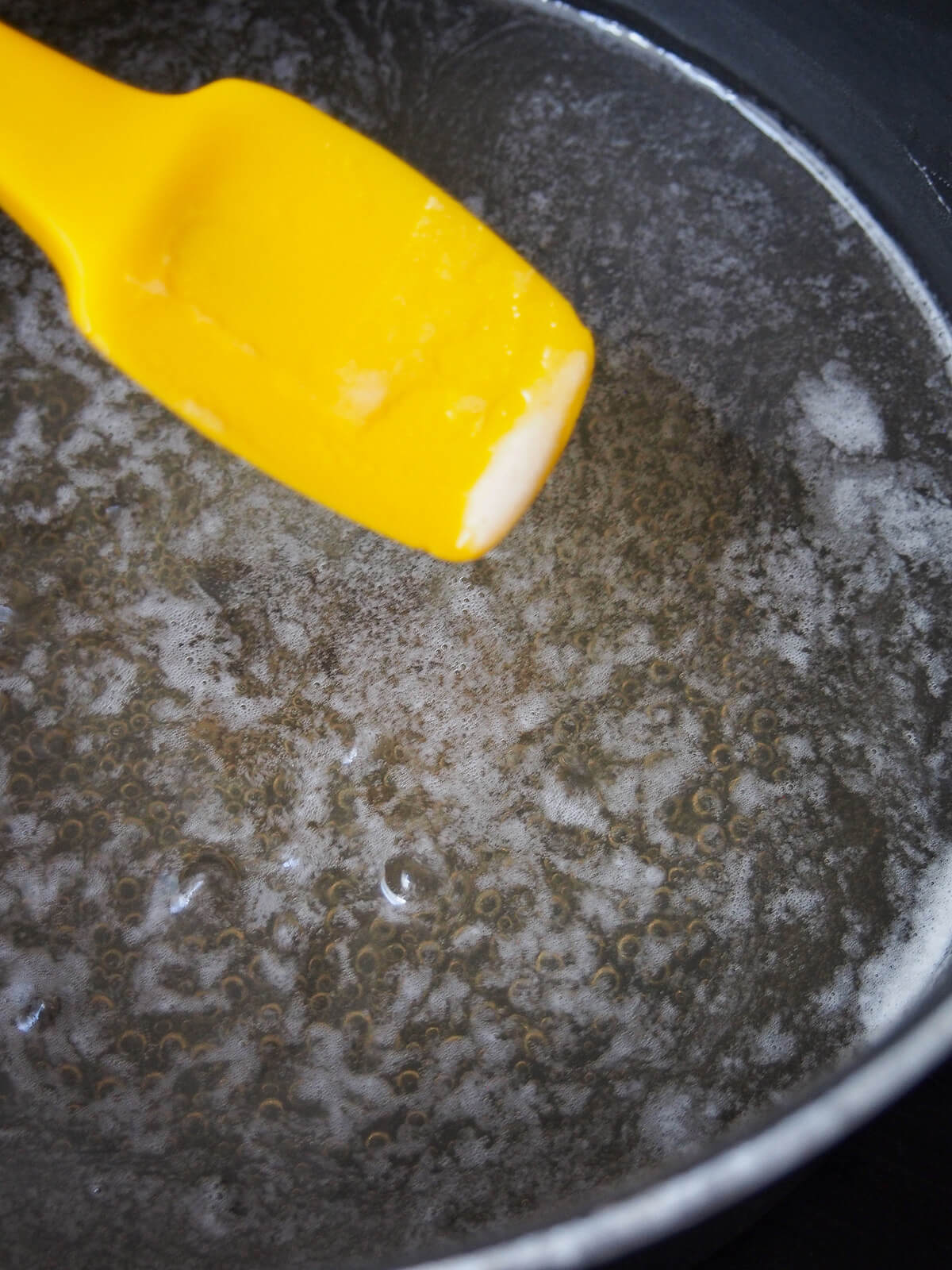 removing foam with spatula from pot of simmering liquid.