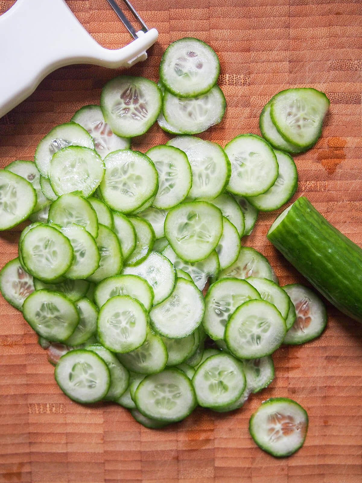 slices of cucumber on chopping board with part cucumber to one side, slice to other.