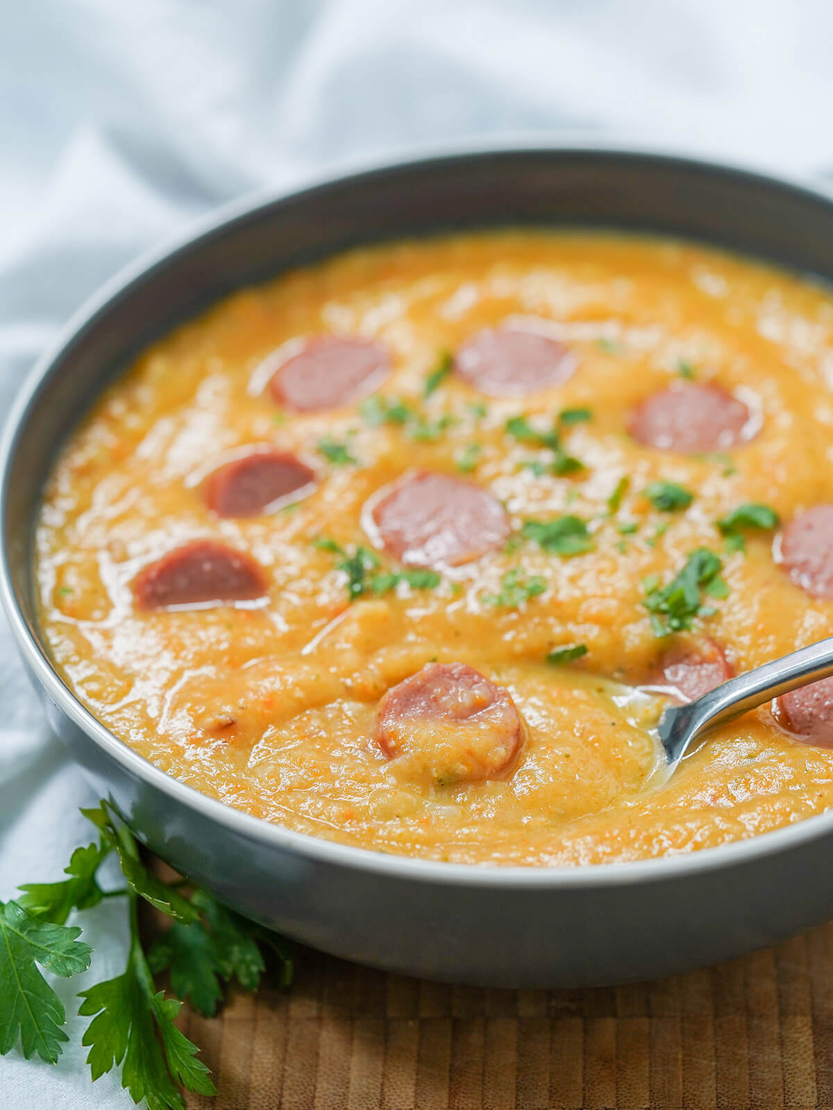 side view of a bowl of German potato soup, kartoffelsuppe, with spoon in bowl.