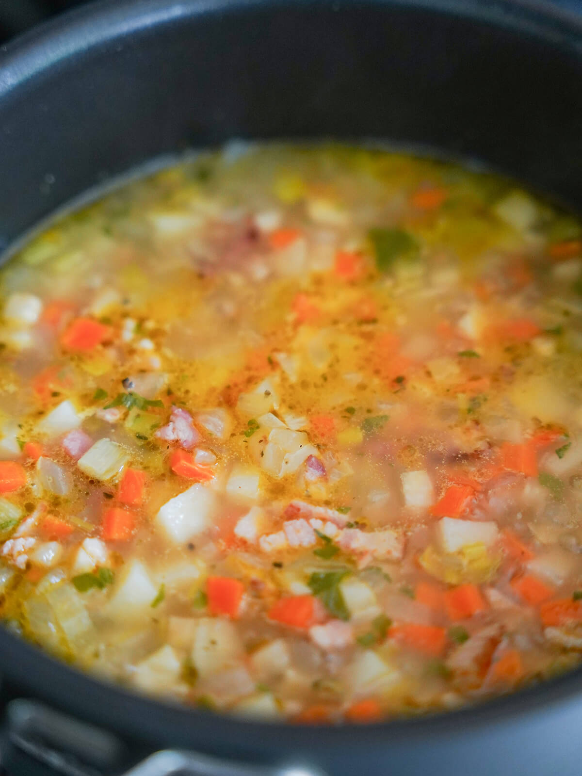 vegetables, bacon and stock in pot.