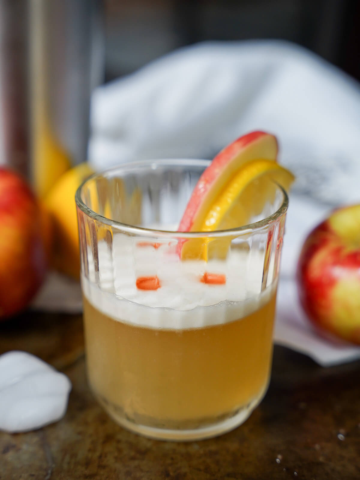 glass of apple whiskey sour with white cloth behind.