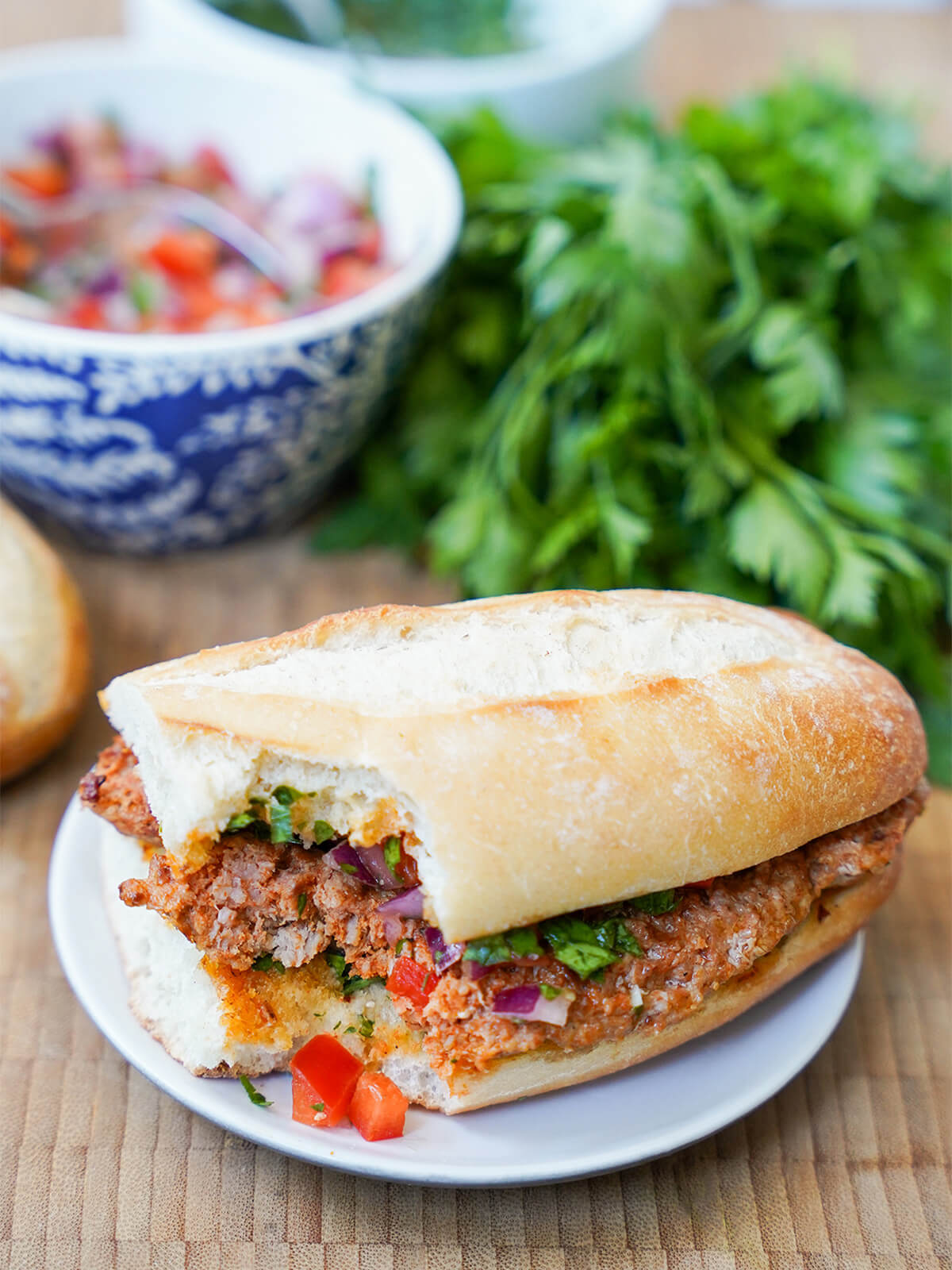 sandwich with bite out of corner and some of salsa fallen onto plate and bowl with more behind.