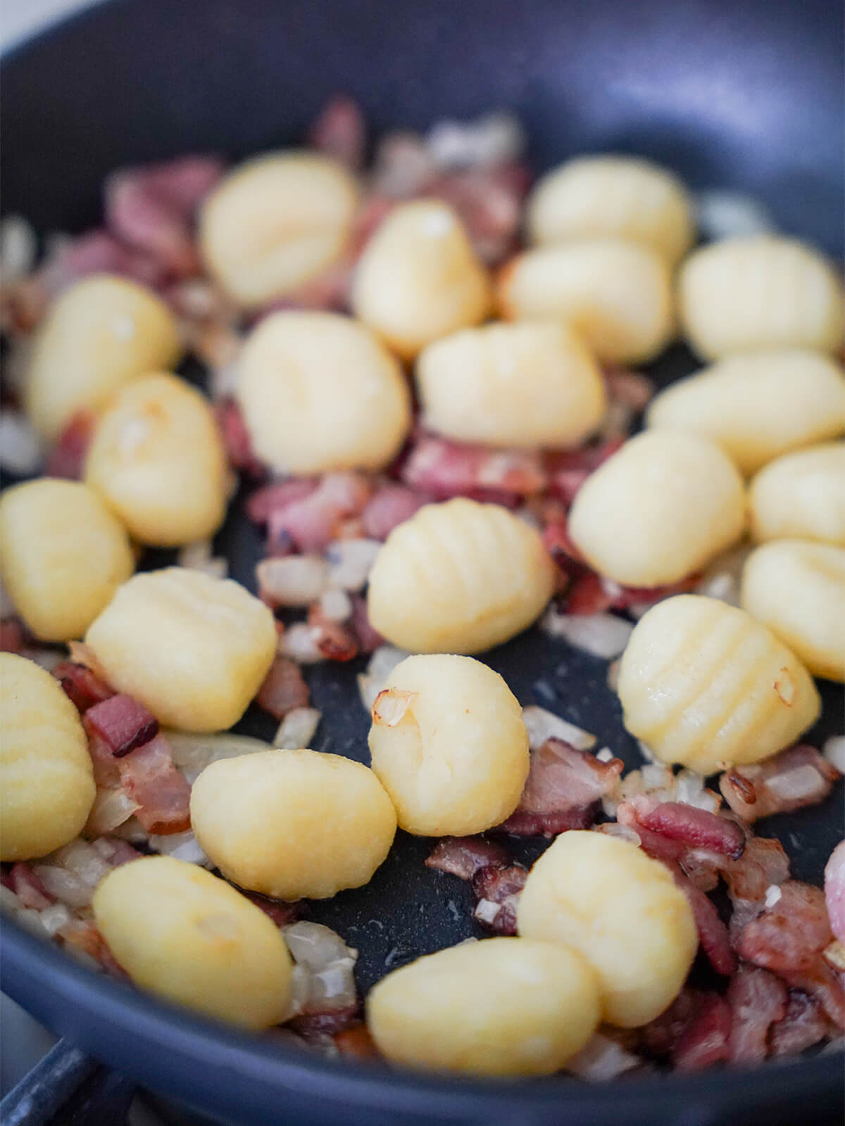 skillet with gnocchi, bacon and onion.