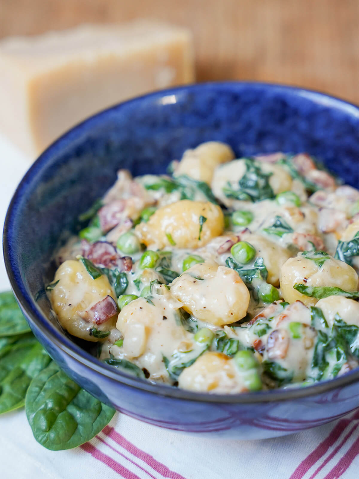 creamy bacon gnocchi with spinach in bowl from side.