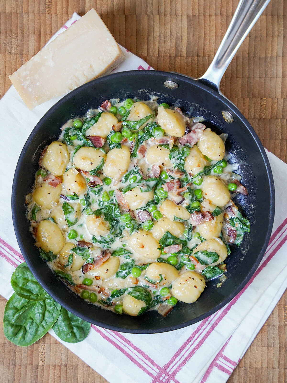 overhead view of skillet with creamy bacon gnocchi with spinach.