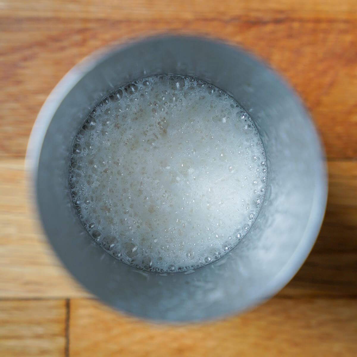 overhead view of cocktail shaker with lots of froth in it.
