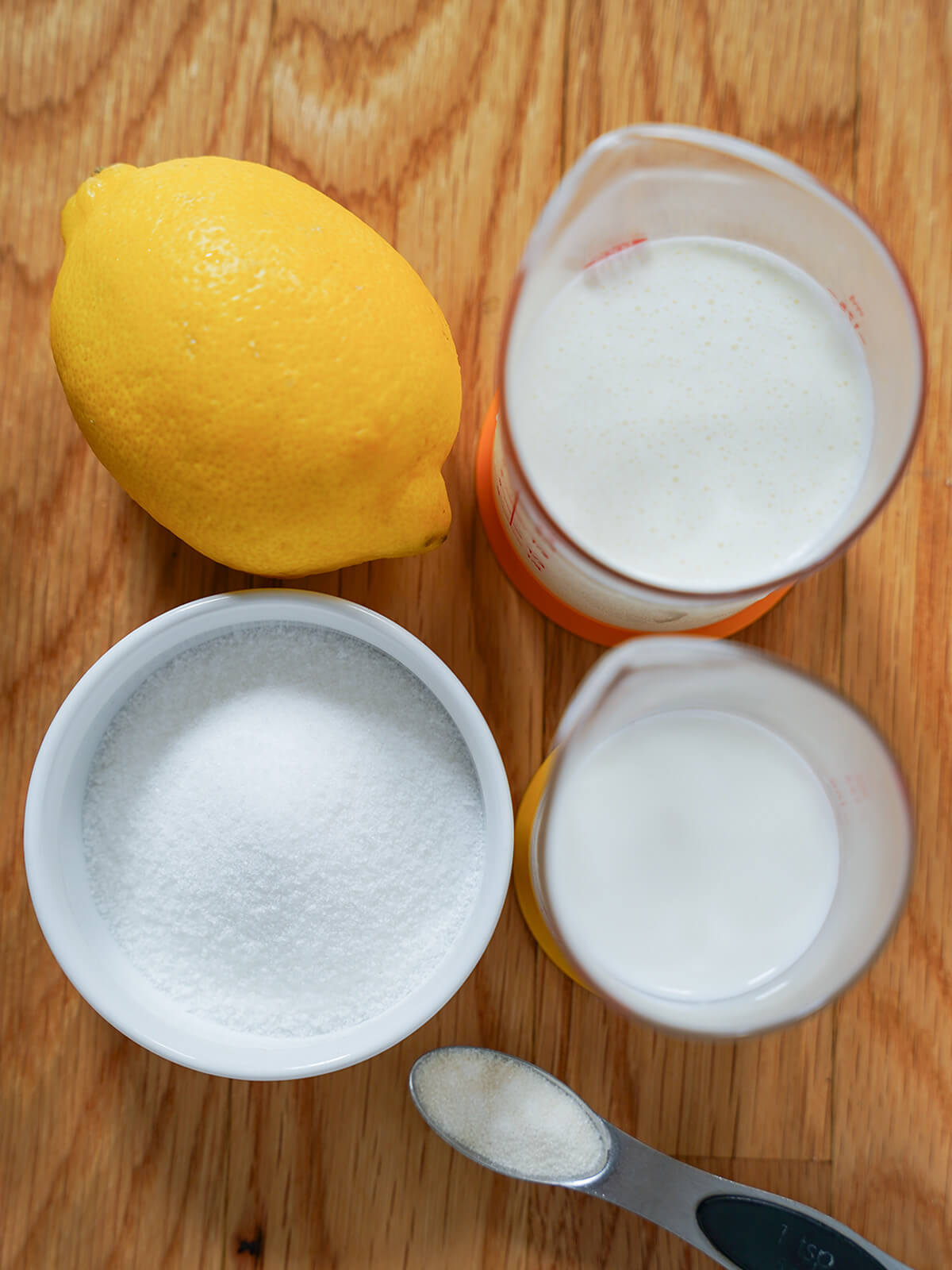 lemon, bowl of sugar, measures with milk and cream and spoonful of gelatin