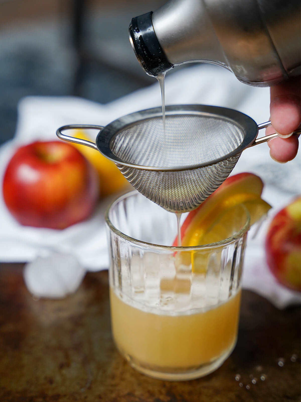 pouring cocktail from shaker through strainer into glass.
