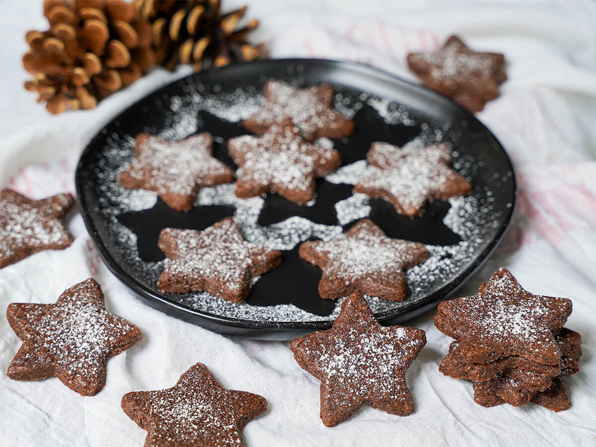 plate of Basler brunsli chocolate almond cookies with some on cloth around plate.