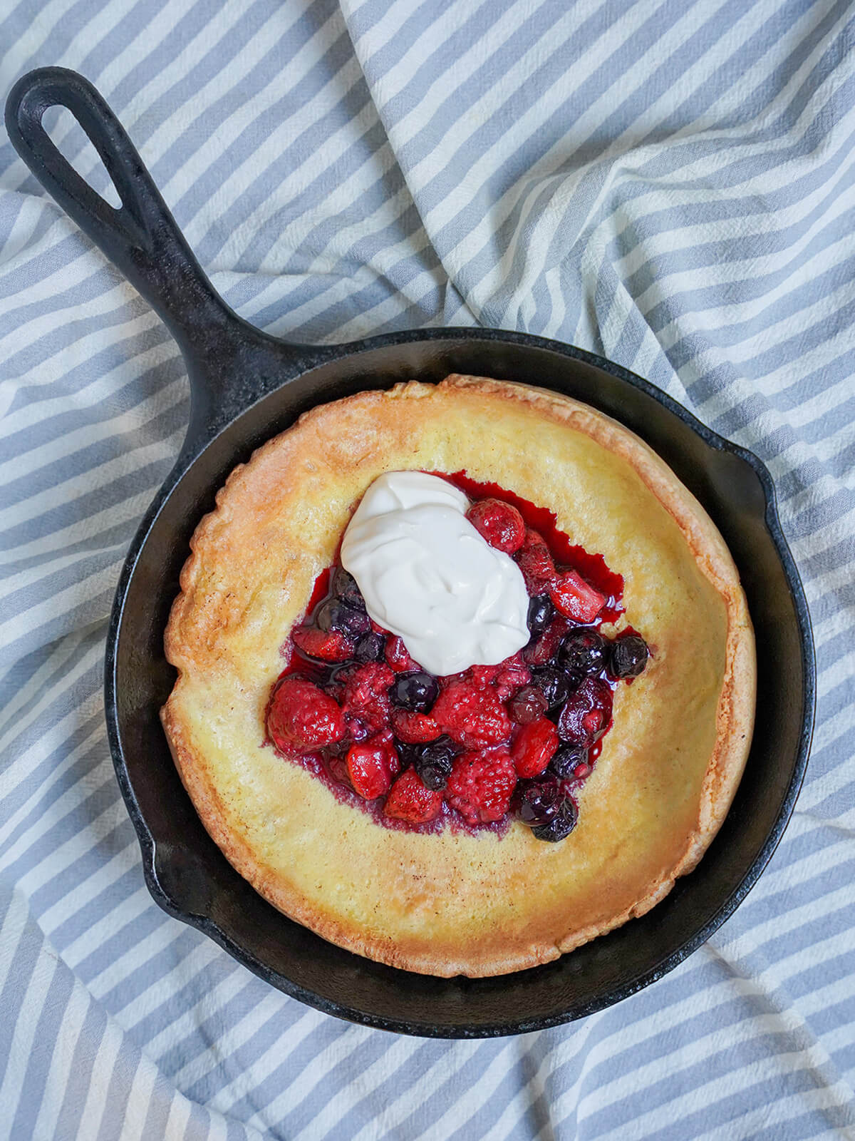 overhead view of small skillet with Individual Dutch baby pancake with berries.