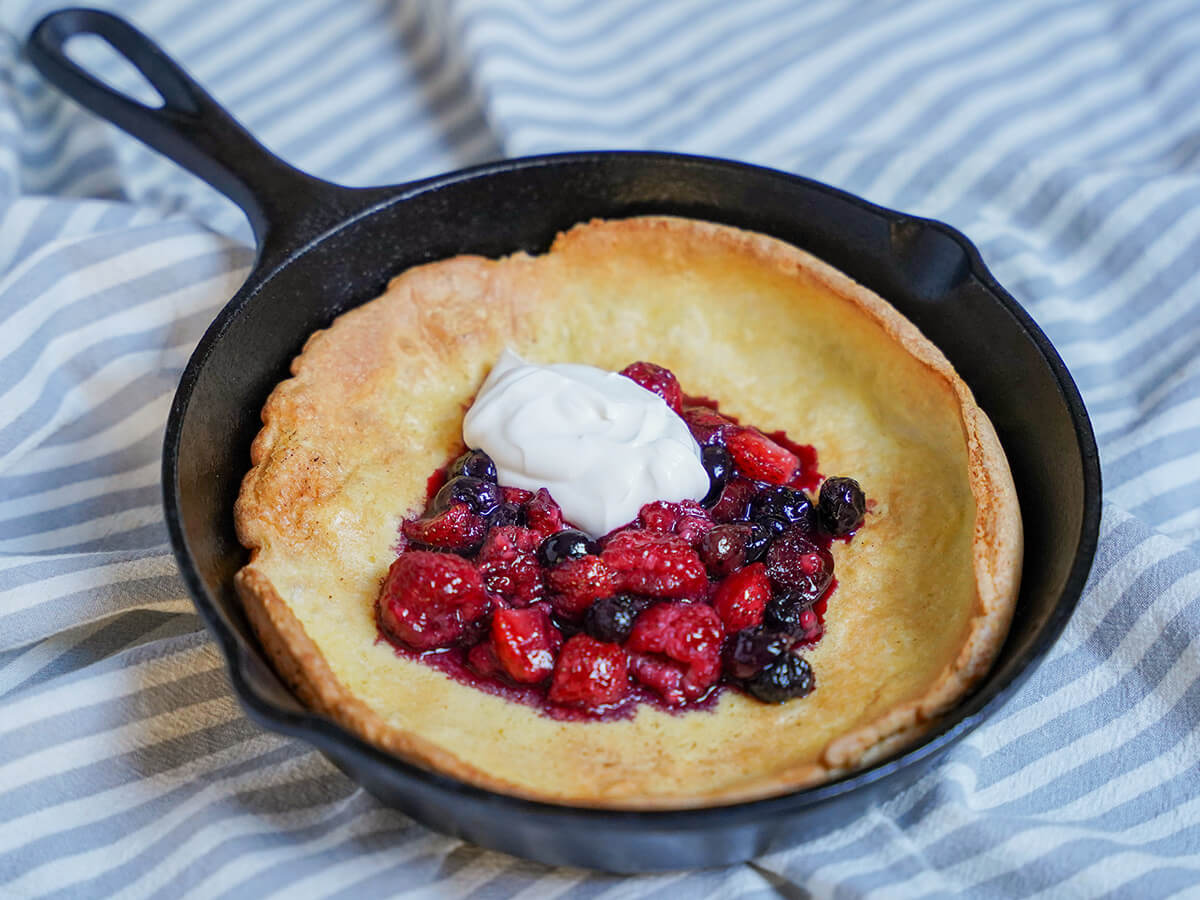 side view of Individual Dutch baby pancake with berries in skillet.
