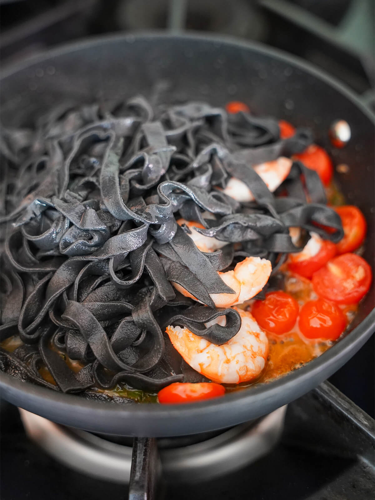 adding pasta into skillet with tomatoes underneath.