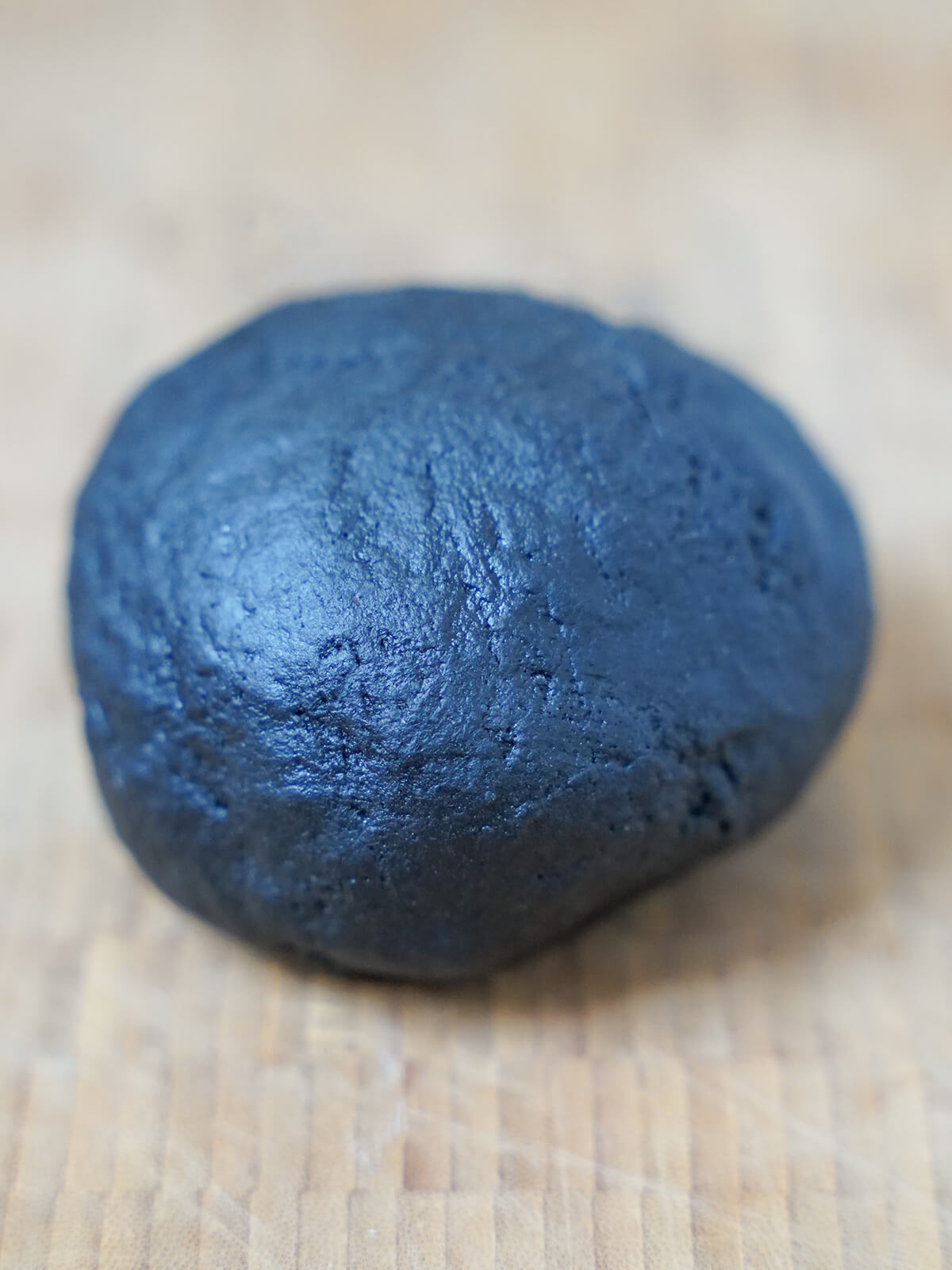 ball of squid ink pasta on chopping board.
