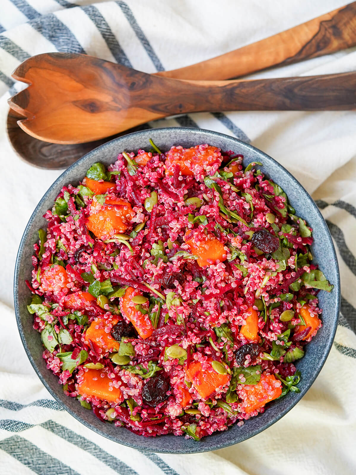 bowl of butternut squash quinoa salad and wooden serving utensils from overhead.