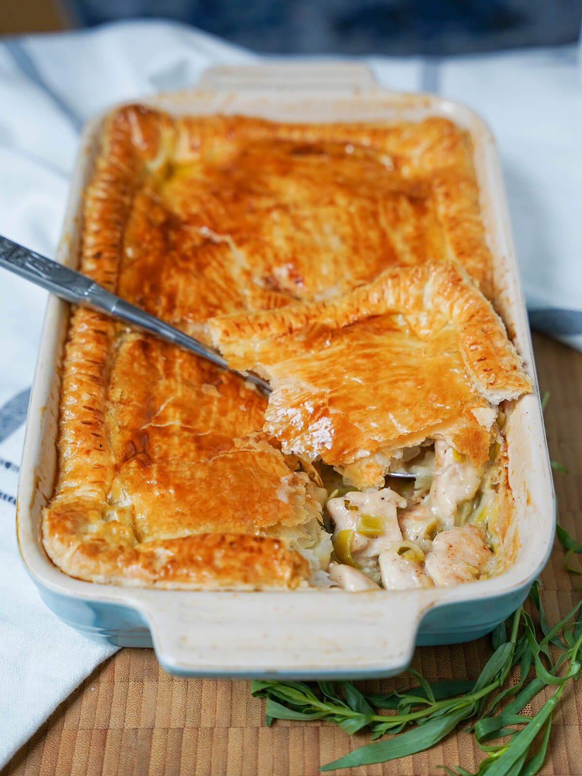 end view of dish of chicken and leek pie with tarragon with spoonful taken showing filling below.