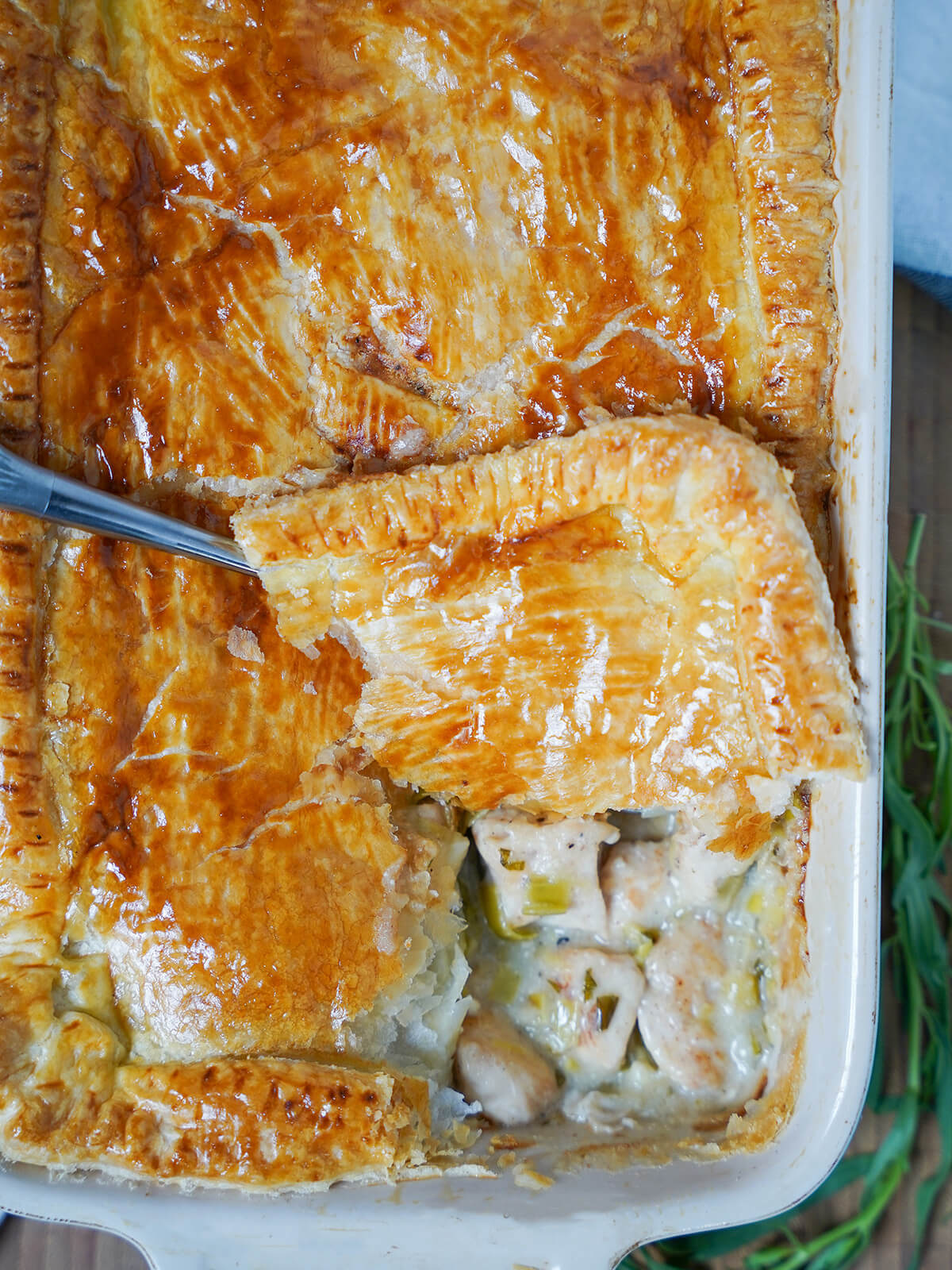 overhead view of chicken and leek pie with tarragon with spoonful of pastry on top showing filling.